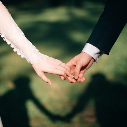 Close up of a bride and groom holding hands